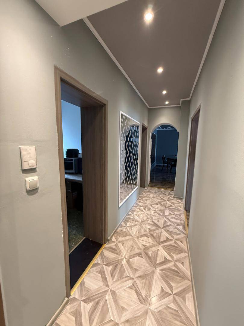 Heller Flur mit gemustertem Boden und Einbaustrahlern.