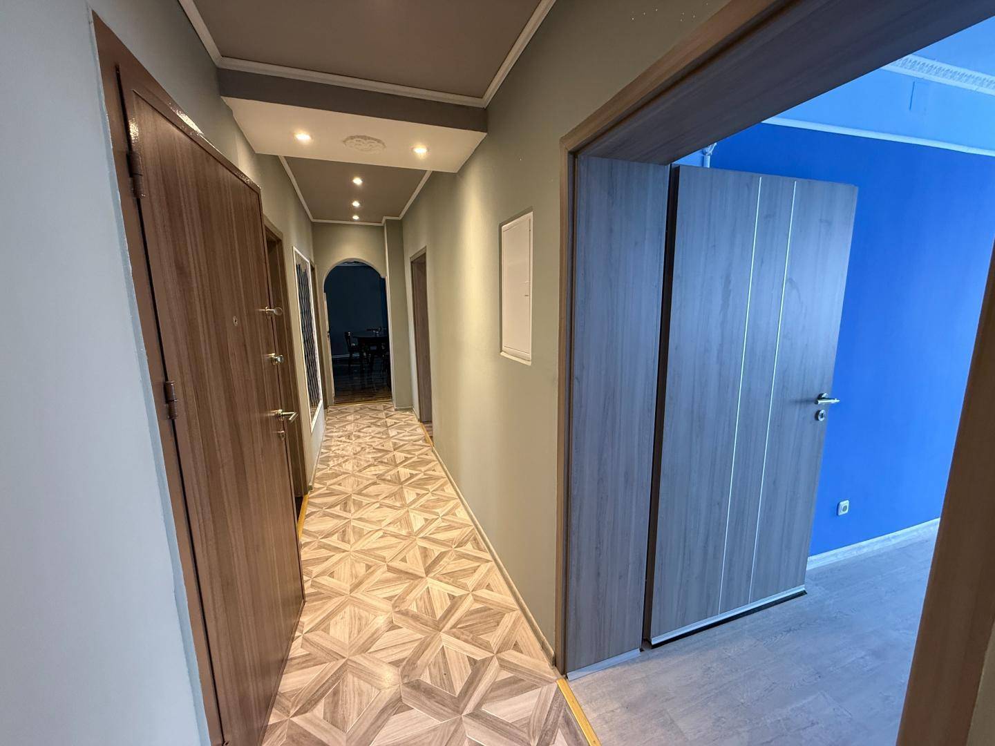 Heller Flur mit gemustertem Boden, Einbaustrahlern und Zugang zu weiteren Räumen.