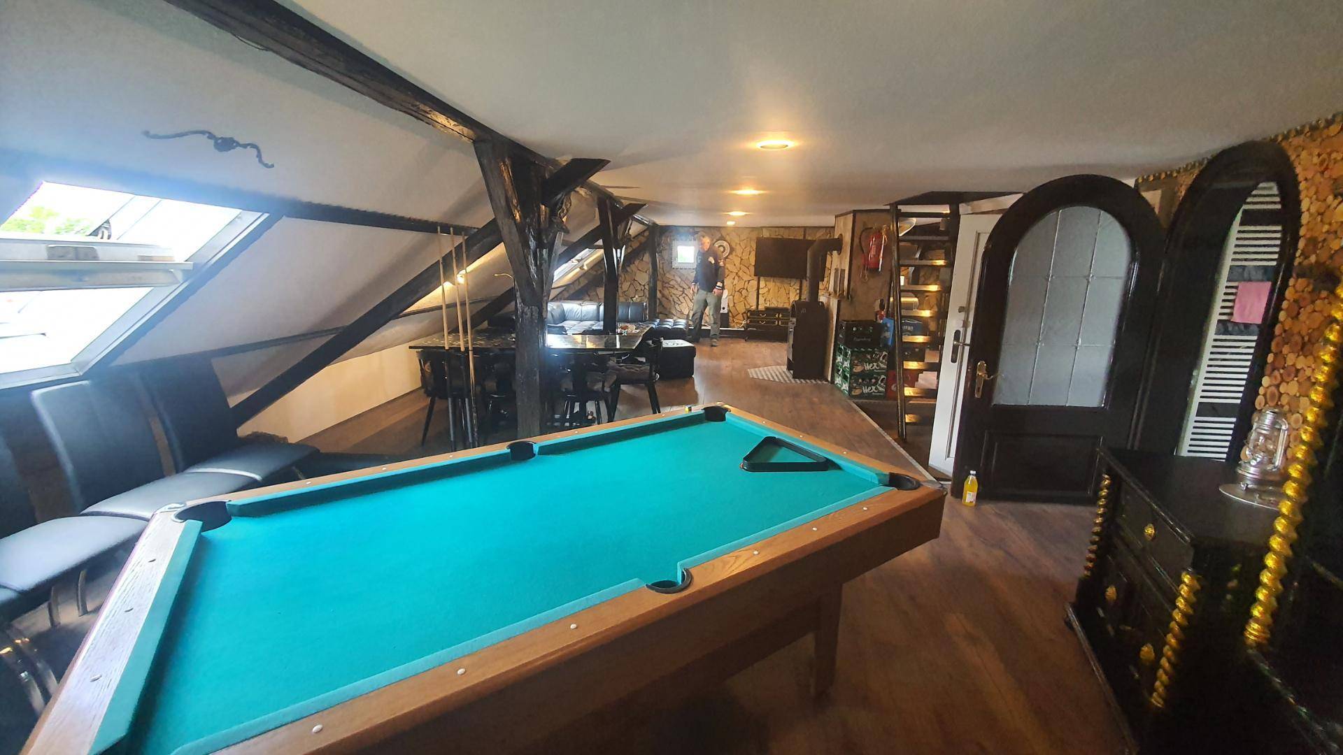Unterhaltungsbereich im Dachgeschoss mit Billardtisch, Dachfenstern und Holzboden.