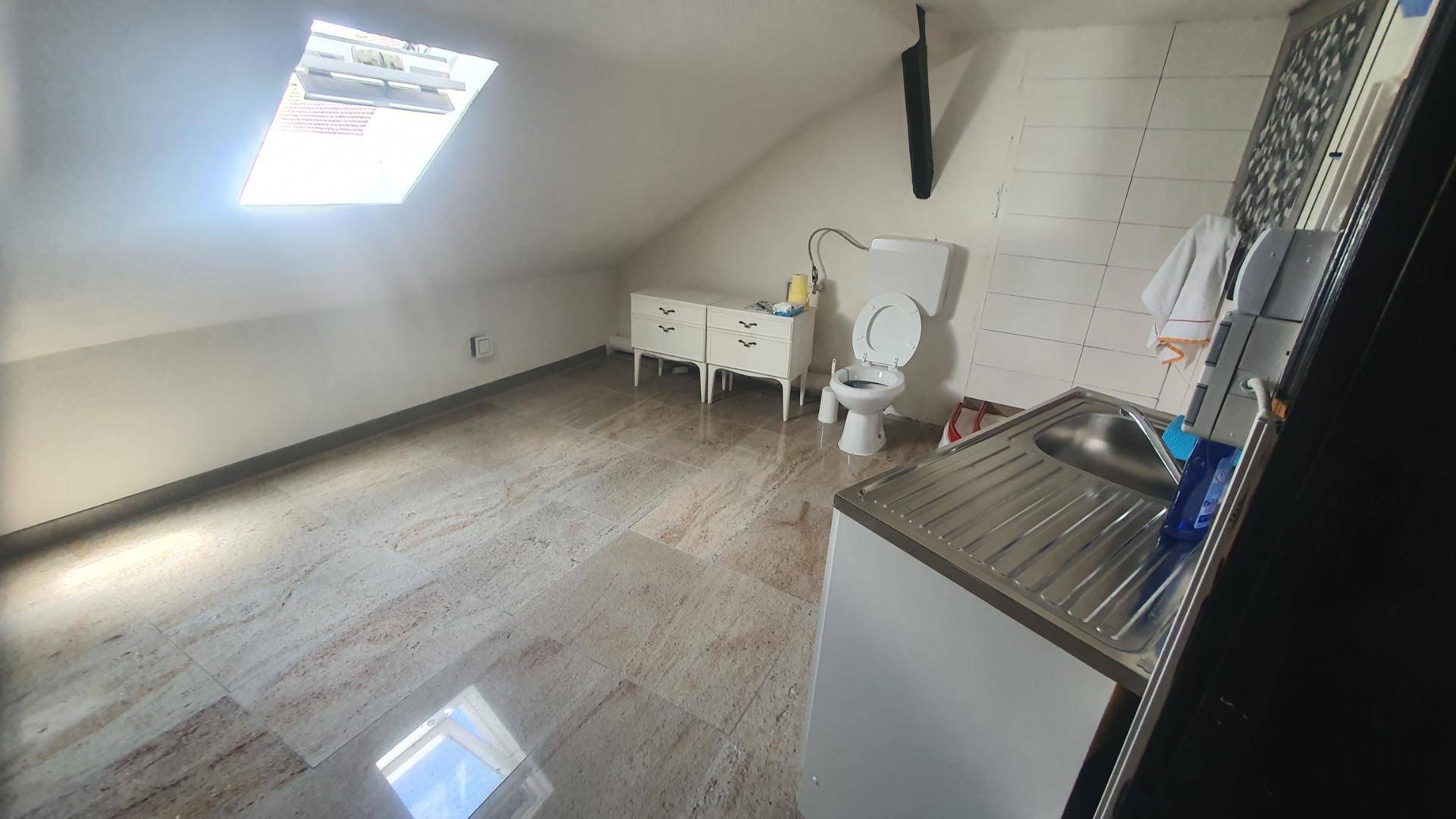 Helles Dachgeschoss-Badezimmer mit Dachfenster, Toilette und Waschbecken.