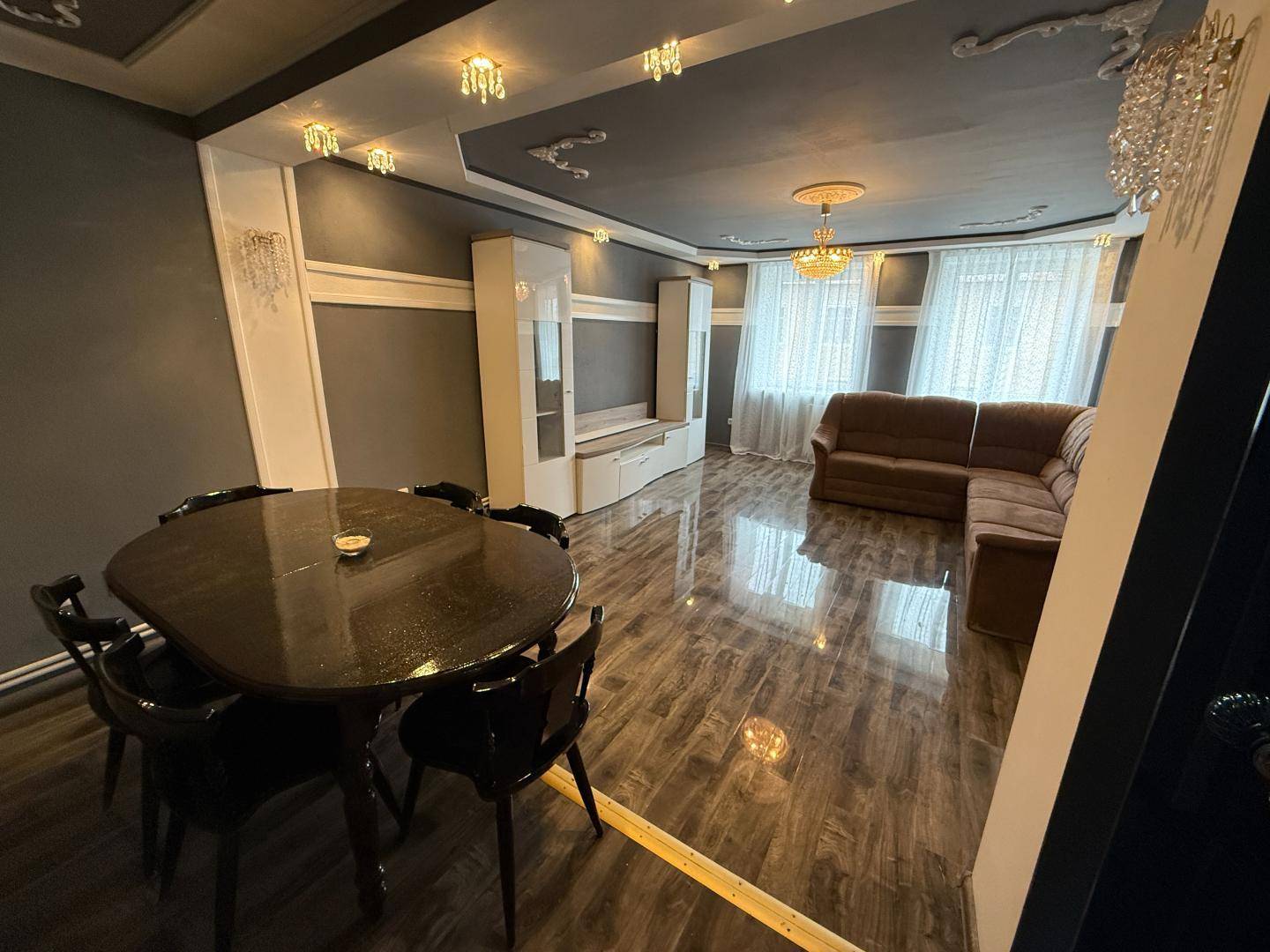 Heller Wohn-Essbereich mit Sofa, Esstisch und großen Fenstern.