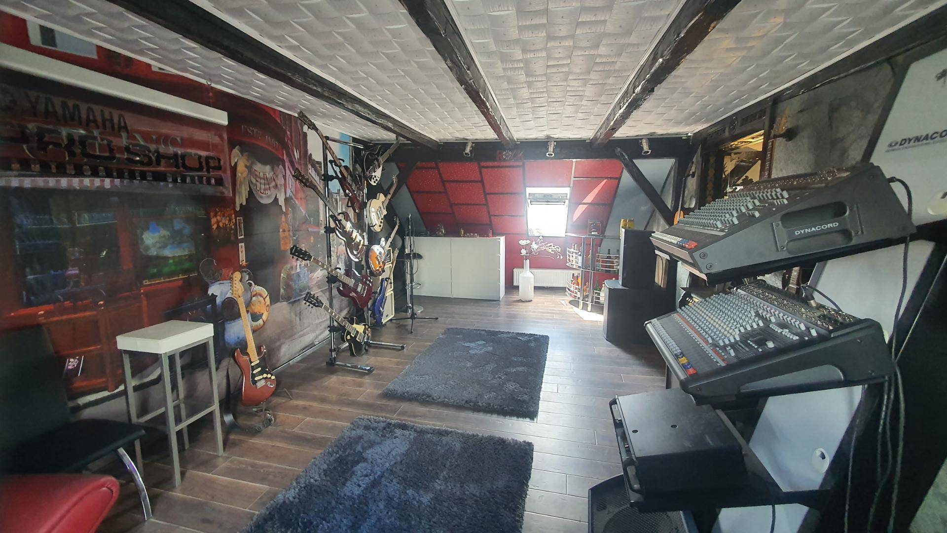 Geräumiger Musikraum im Dachgeschoss mit Holzbalken und Instrumenten.