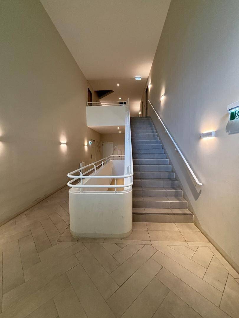 Treppenhaus mit hellem Fliesenboden und modernem Geländer in der Wohnanlage.