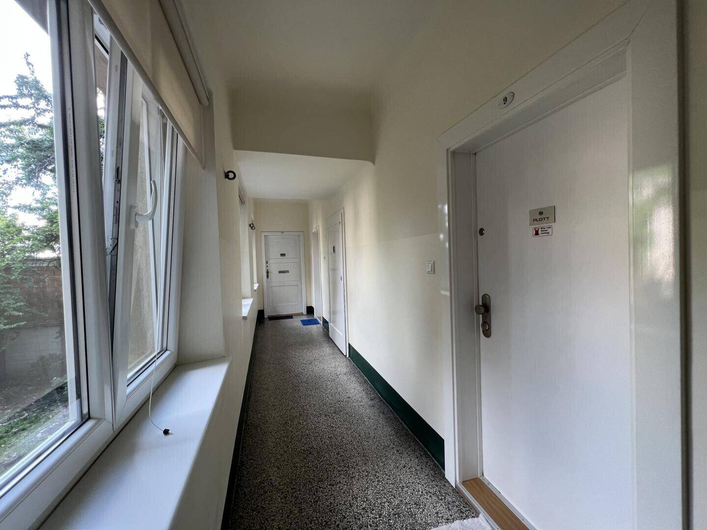 Gemeinschaftsflur mit Fenstern und mehreren Wohnungstüren in einem Mehrfamilienhaus.