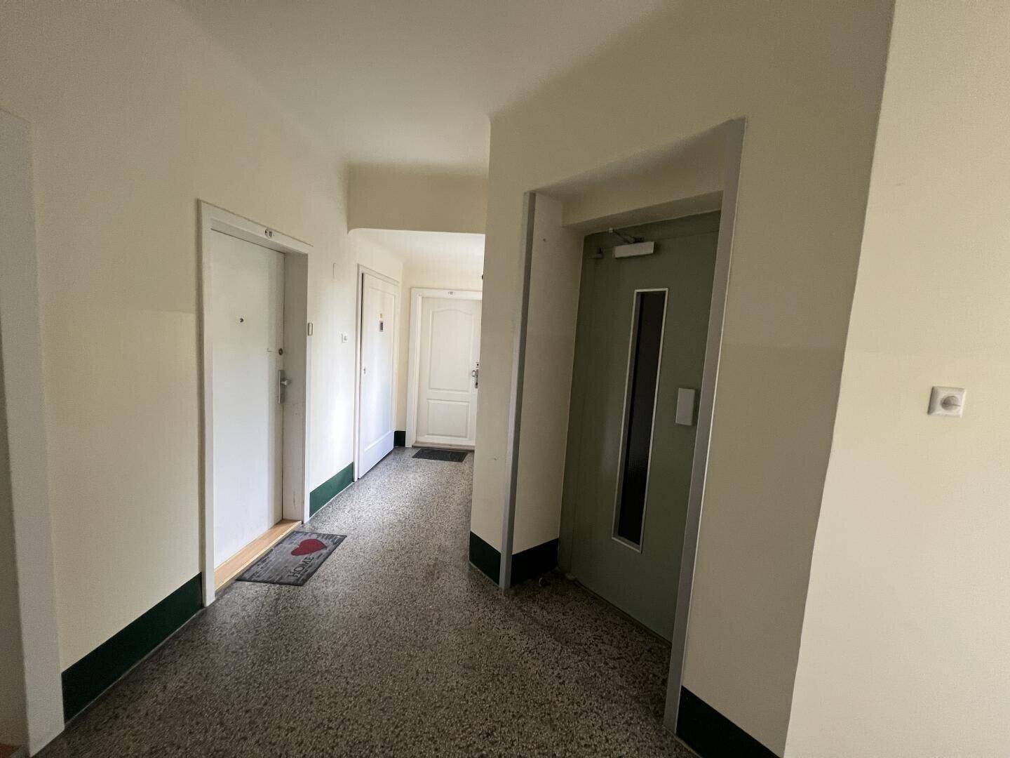 Heller Hausflur mit Aufzug und Zugang zu den einzelnen Wohneinheiten.