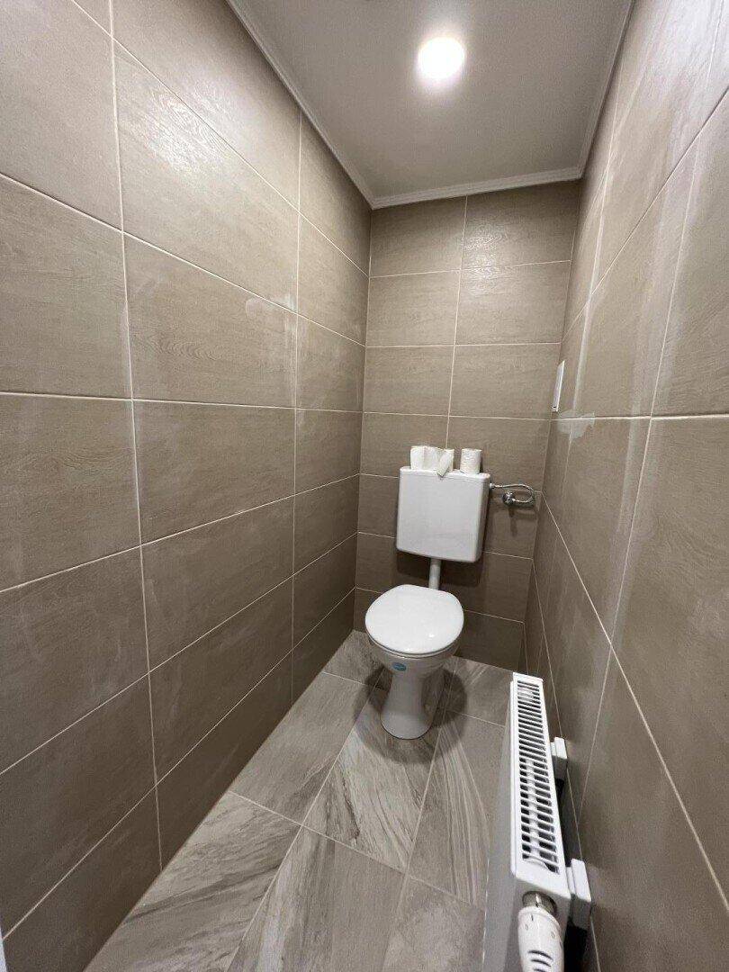 Separates WC mit beigefarbenen Fliesen an Wänden und Boden sowie einem Heizkörper.