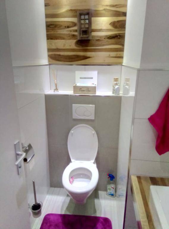 Modernes Gäste-WC mit wandhängender Toilette und Holzvertäfelung an der Wand.