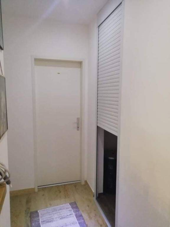 Heller Flur mit Eingangstür und einem praktischen, rollladenverdeckten Stauraum.