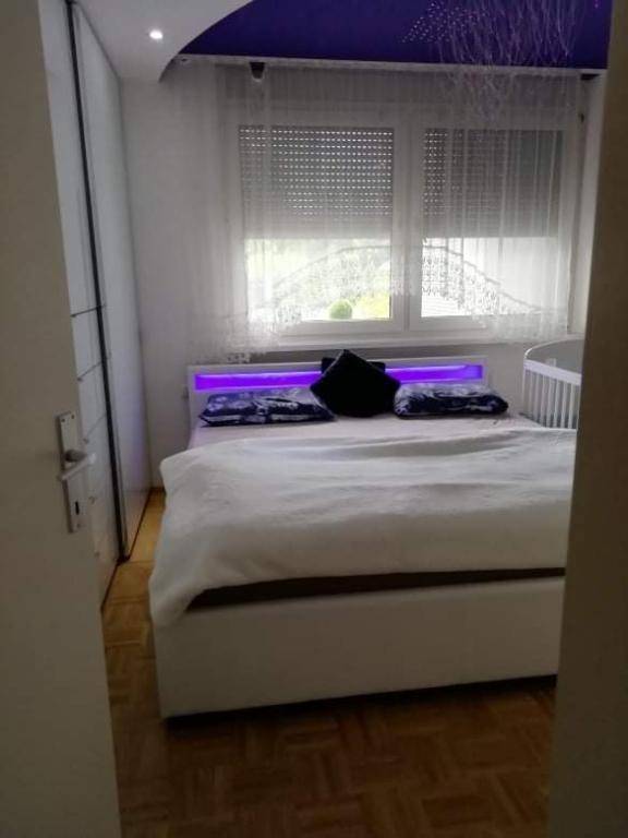 Schlafzimmer mit Doppelbett, Parkettboden und Fenster mit Rollläden und Vorhängen.