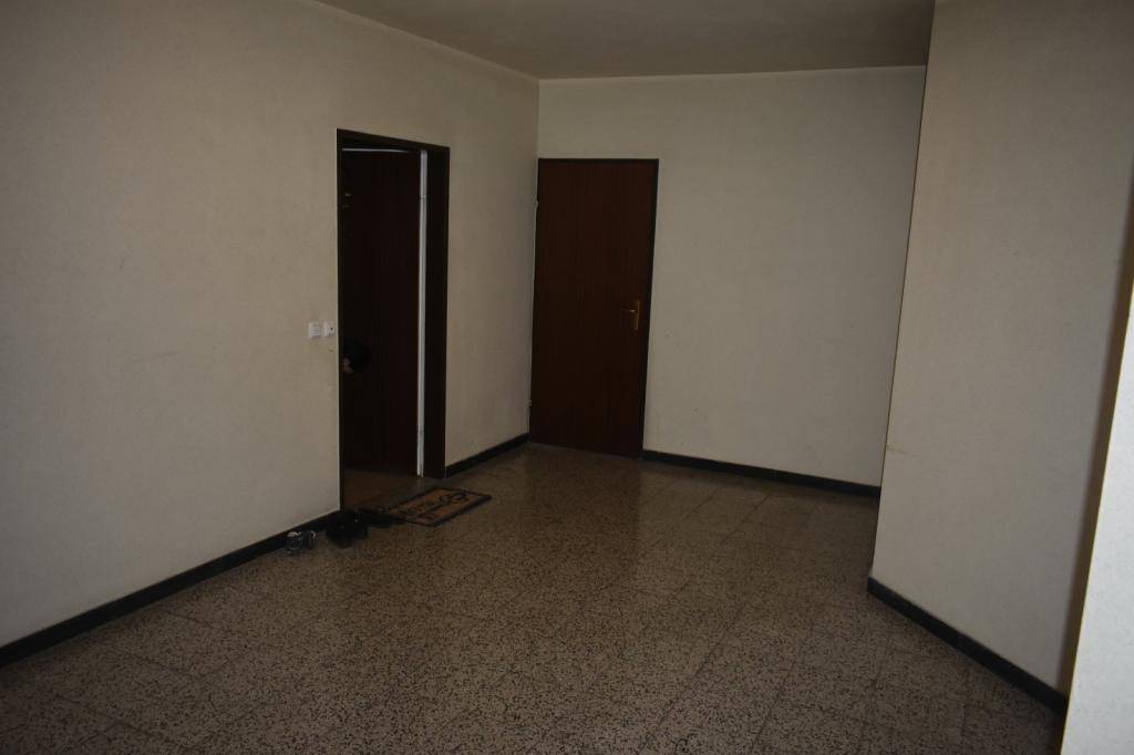 Leerer Raum mit Fliesenboden und zwei Türen, bereit zur individuellen Gestaltung.