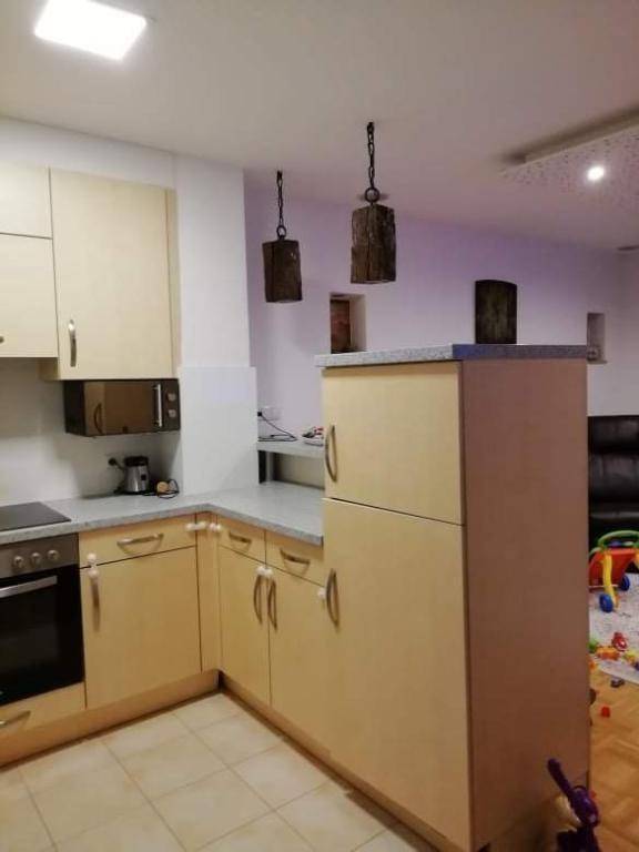 Helle Küche mit Einbauschränken, Mikrowelle und Fliesenboden, offen zum Wohnbereich.