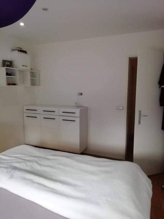 Schlafzimmer mit modernem Bett und Kommode, hellen Wänden und Parkettboden.