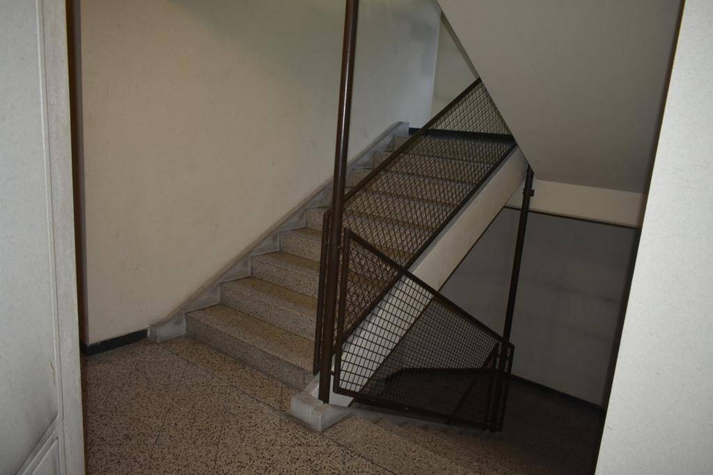 Treppenhaus mit Steinstufen und Metallgeländer, das verschiedene Etagen verbindet.