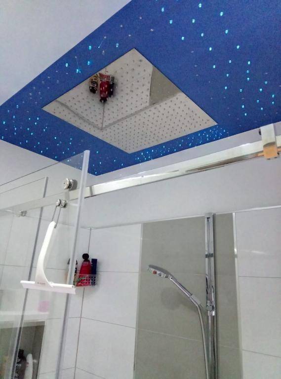 Duschbereich mit großer Regendusche und einer blauen Decke mit Sternenhimmel-Beleuchtung.