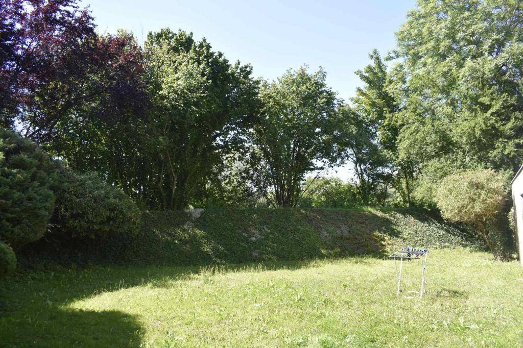 Gepflegter Gartenbereich mit Rasenfläche und üppiger Bepflanzung im Hintergrund.