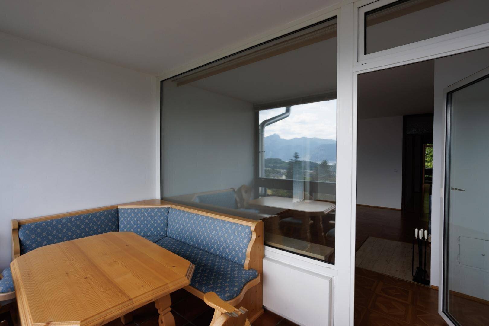 Gemütliche Sitzecke mit Holztisch und Bank, bietet einen weiten Blick auf See und Berge.