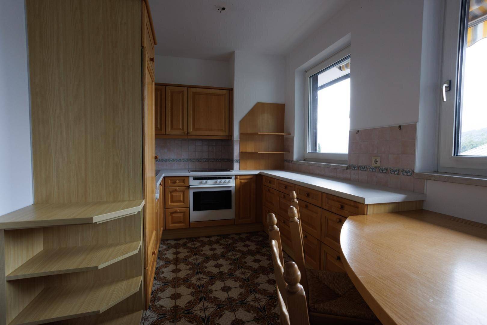 Küche mit Holzschränken, gemustertem Fliesenboden und einem integrierten Backofen.