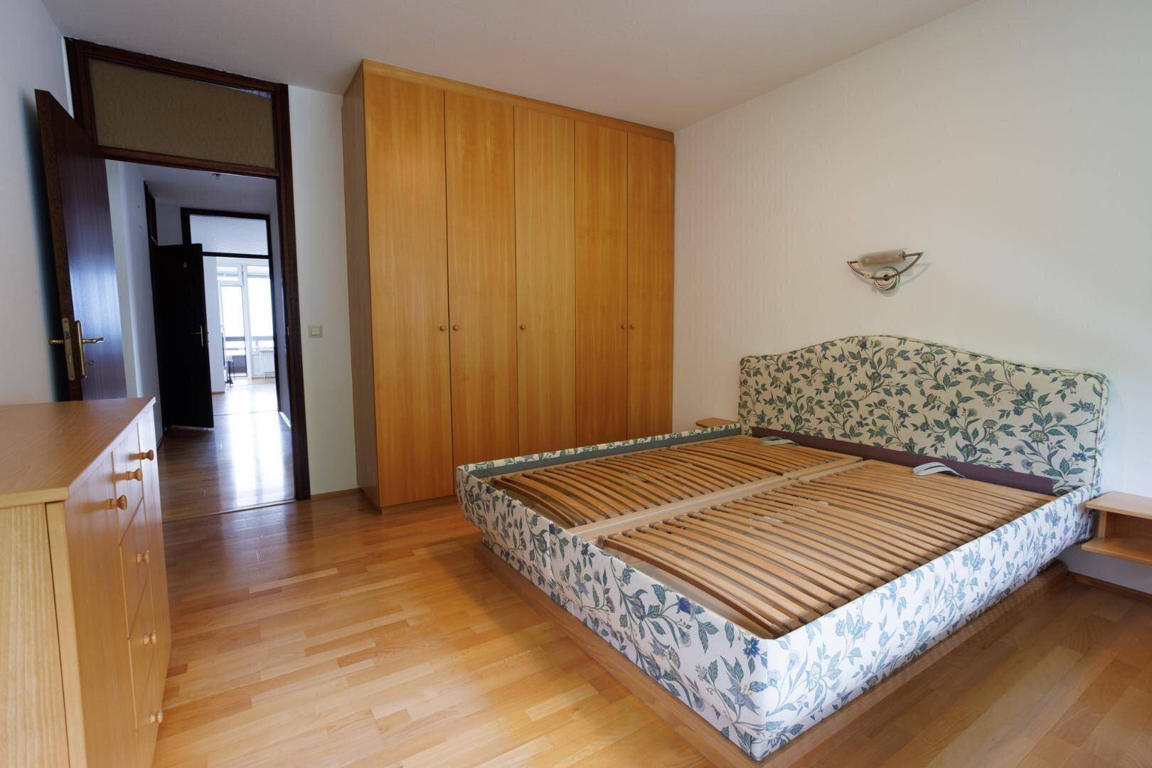 Schlafzimmer mit Holzboden, Bettgestell und geräumigen Einbauschränken aus Holz.