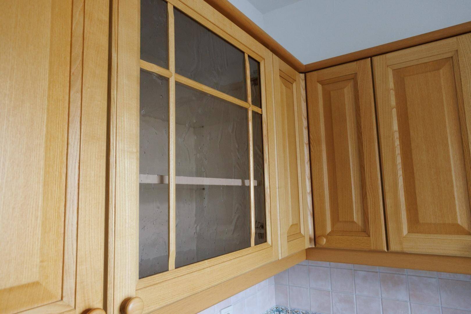 Nahaufnahme von Holz-Küchenschränken, einer davon mit einer Glasfront.