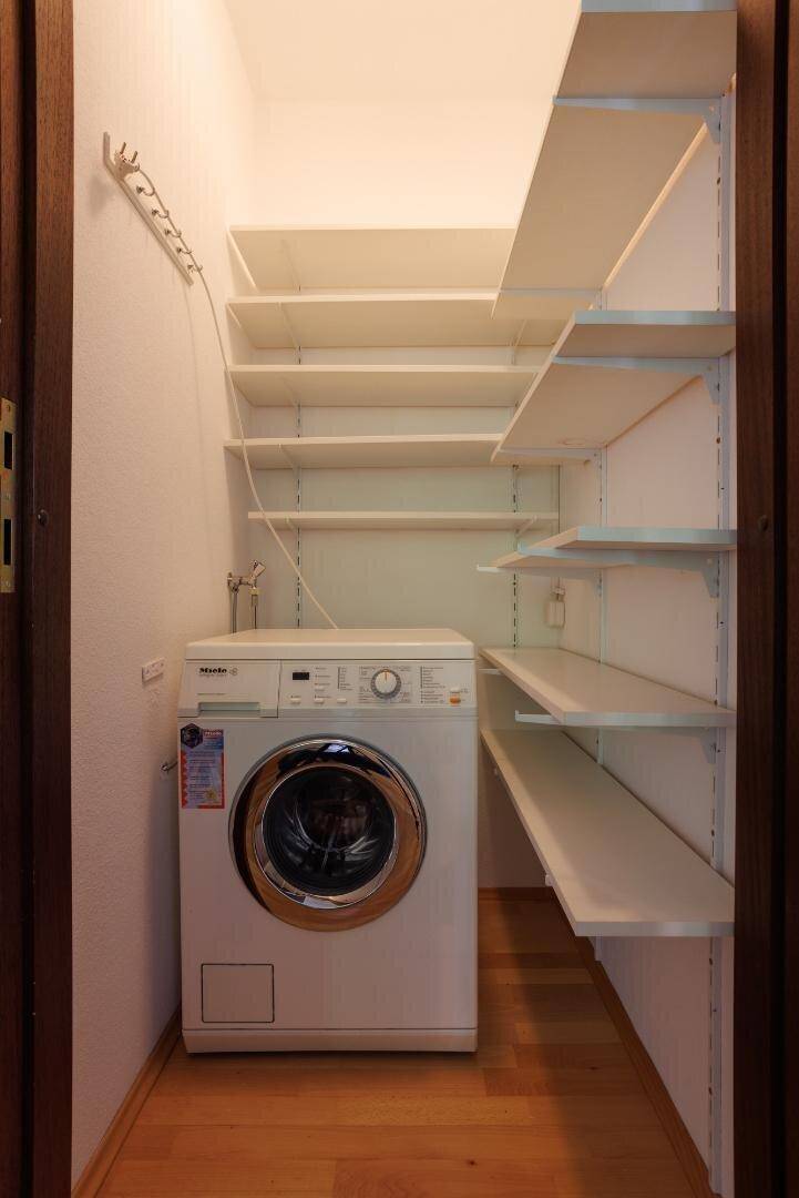 Hauswirtschaftsraum mit Waschmaschine und praktischen Wandregalen für Stauraum.