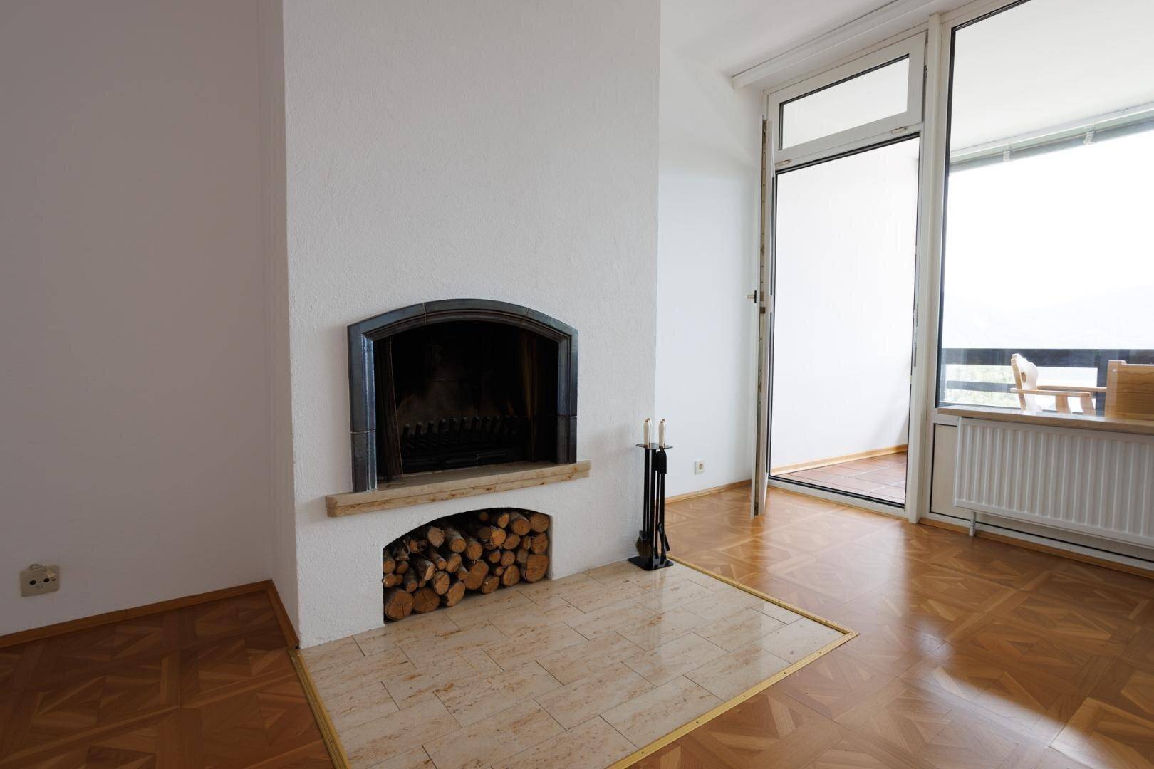 Nahaufnahme des Kamins im Wohnzimmer mit gestapeltem Brennholz und Kaminbesteck.