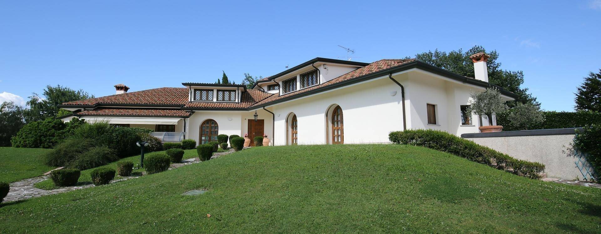 Weitläufige Ansicht der weißen Villa mit Terrakottadach und hügeligem Rasen.