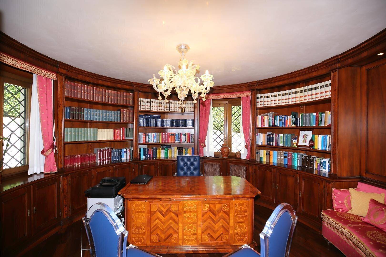 Elegantes Büro mit runden, holzvertäfelten Bücherregalen und einem großen Schreibtisch.