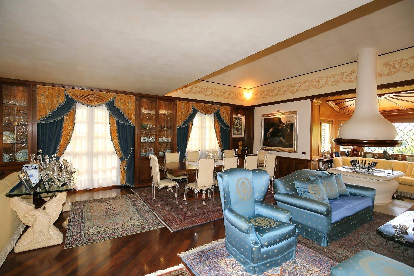Großer Wohn- und Essbereich mit eleganten Vorhängen, Holzböden und einem Kamin.