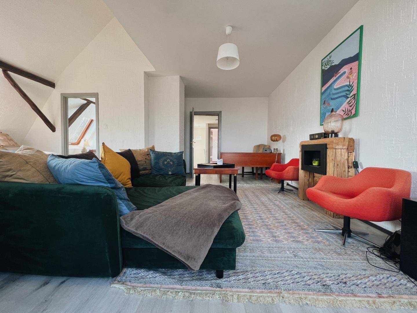 Geräumiges Wohnzimmer mit gemütlichem Sofa, Teppich und Zugang zu weiteren Räumen.