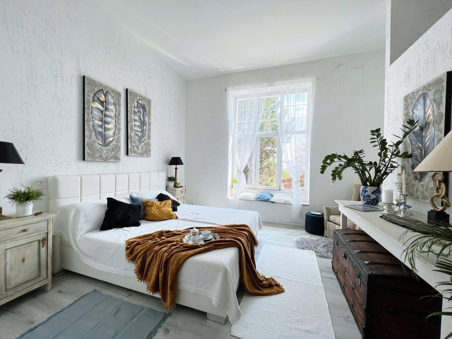 Helles Schlafzimmer mit großem Doppelbett, weißen Wänden und Fenster mit Ausblick.