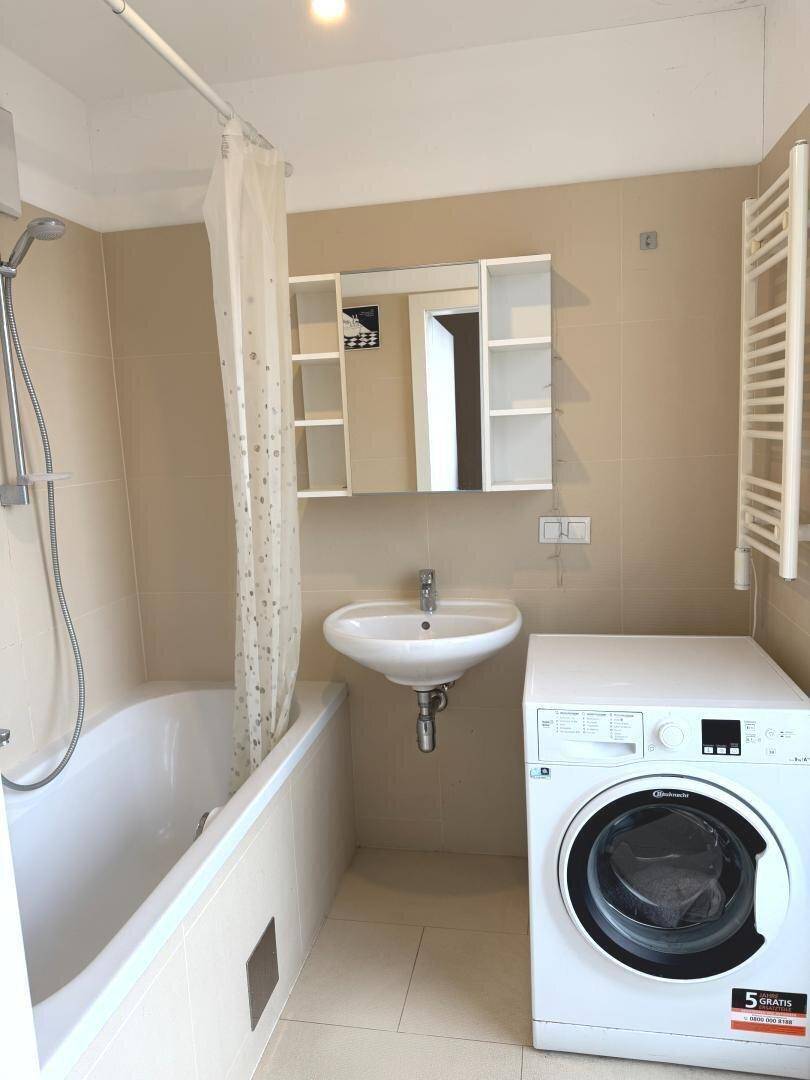 Badezimmer mit Badewanne, Waschbecken, Waschmaschine und beheiztem Handtuchhalter.