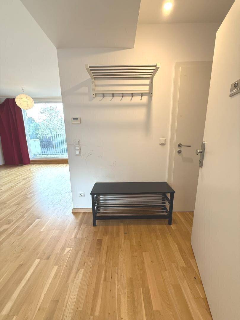 Eingangsbereich mit Holzboden, Garderobe und Blick in den offenen Wohnbereich.