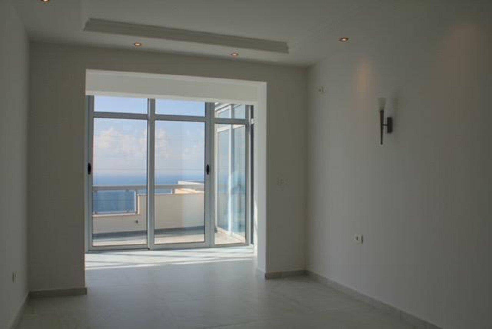 Heller Wohnraum mit Zugang zu einem Außenbereich und Blick auf das Meer.