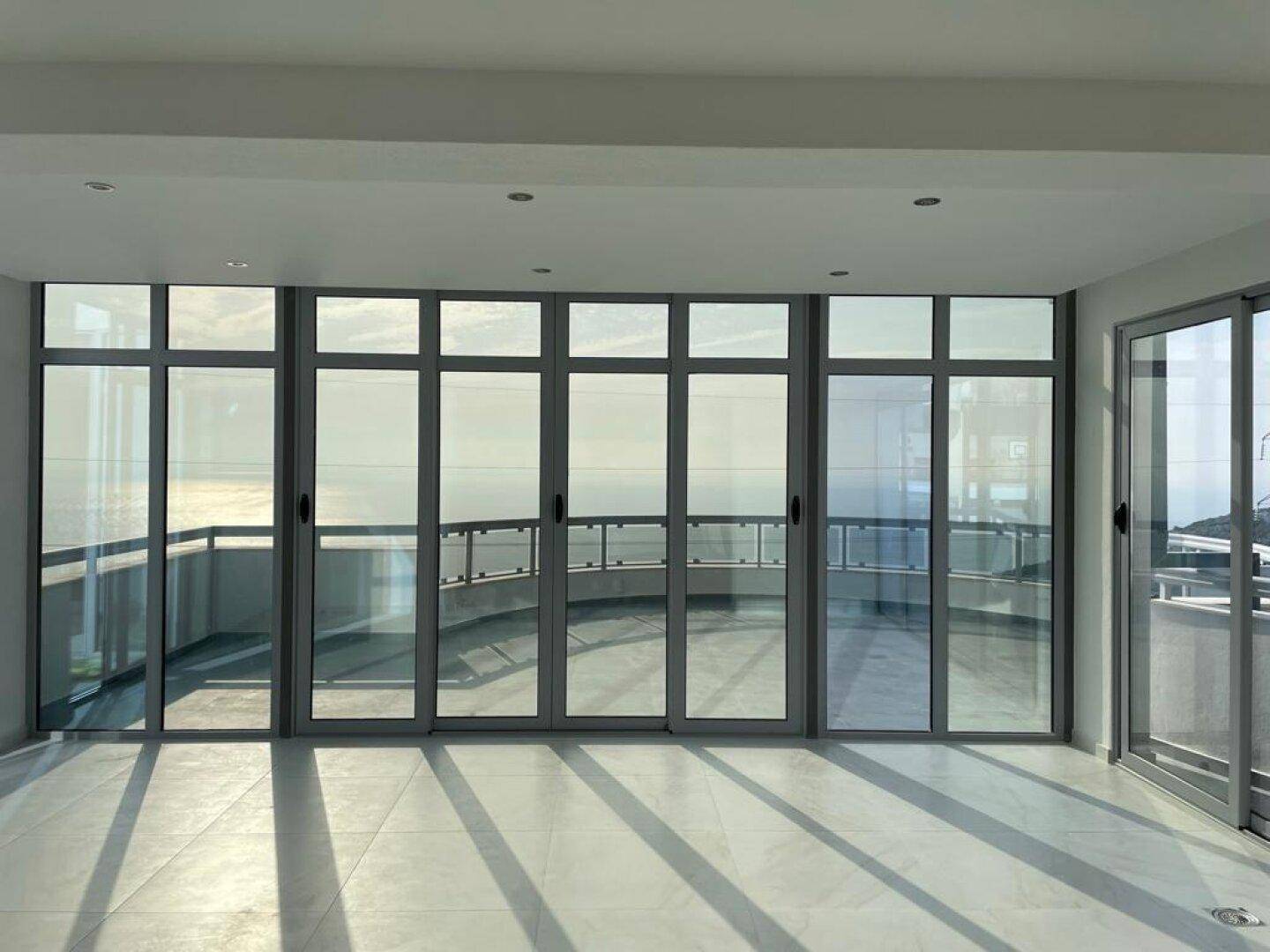 Heller Wohnraum mit großen Fenstern und Zugang zu einer Terrasse mit Meerblick.
