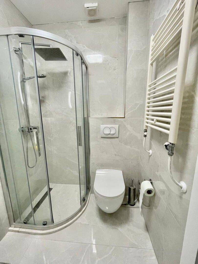 Modernes Badezimmer mit Duschkabine, wandhängendem WC und beheiztem Handtuchhalter.