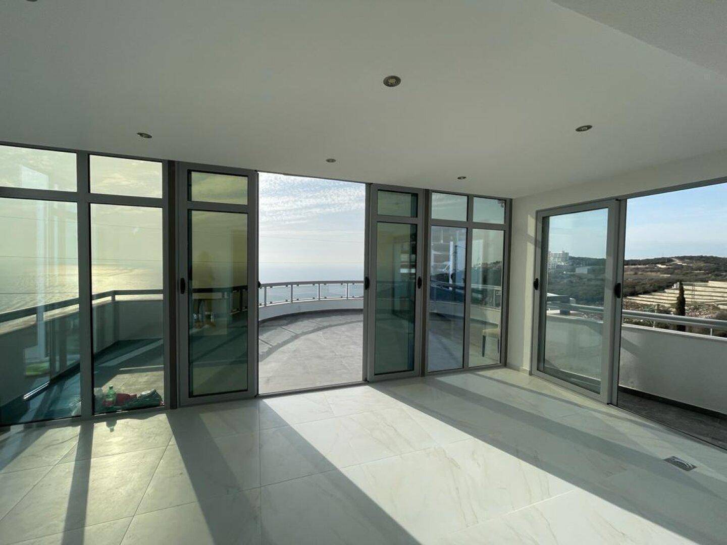 Geräumiger Wohnbereich mit Panoramafenstern, die einen weiten Blick auf das Meer und die Umgebung bieten.