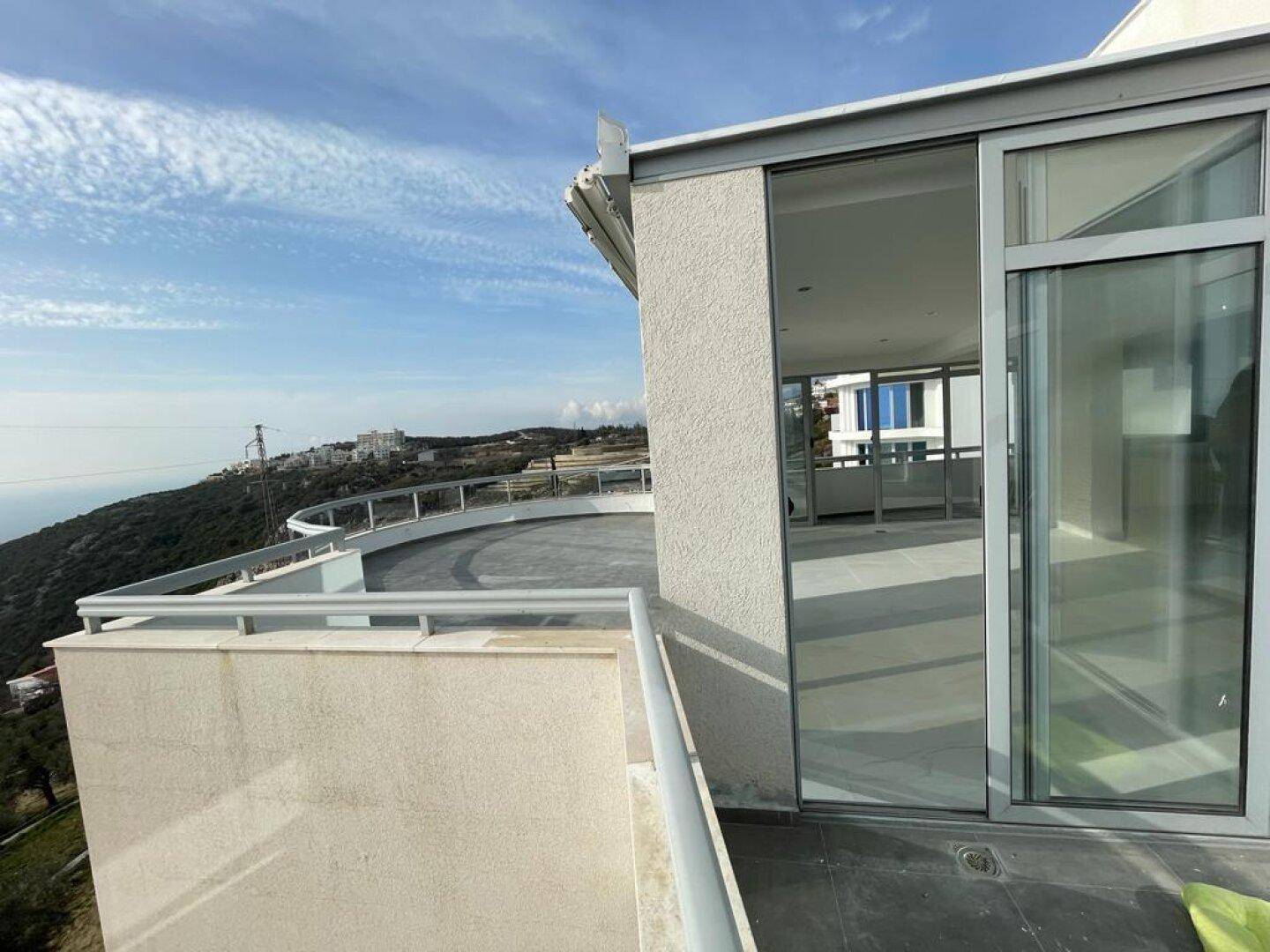Balkon mit Blick auf die moderne Architektur des Gebäudes und die hügelige Landschaft.