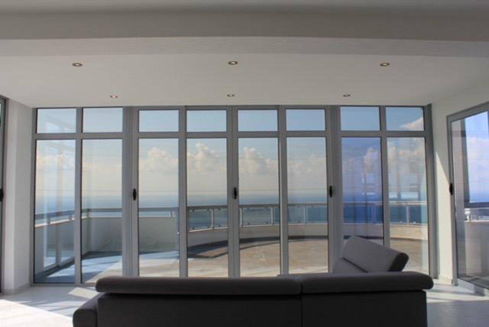 Heller Wohnbereich mit modernem Sofa und großen Fenstern mit weitem Meerblick.