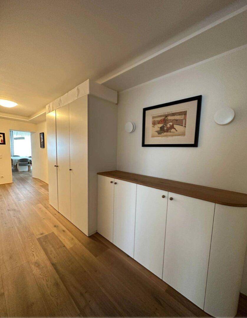 Heller Flur mit Einbauschränken, Holzboden und dekorativem Bild.