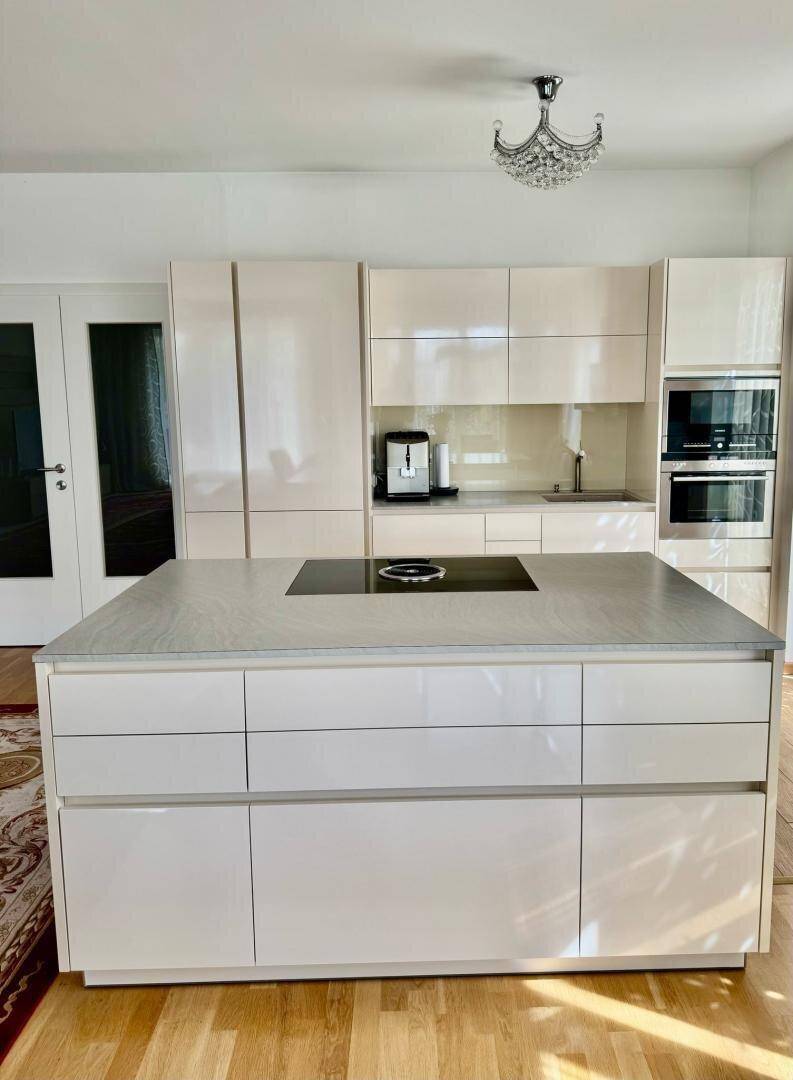 Elegante moderne Küche mit weißer Hochglanz-Kücheninsel und integrierten Geräten.