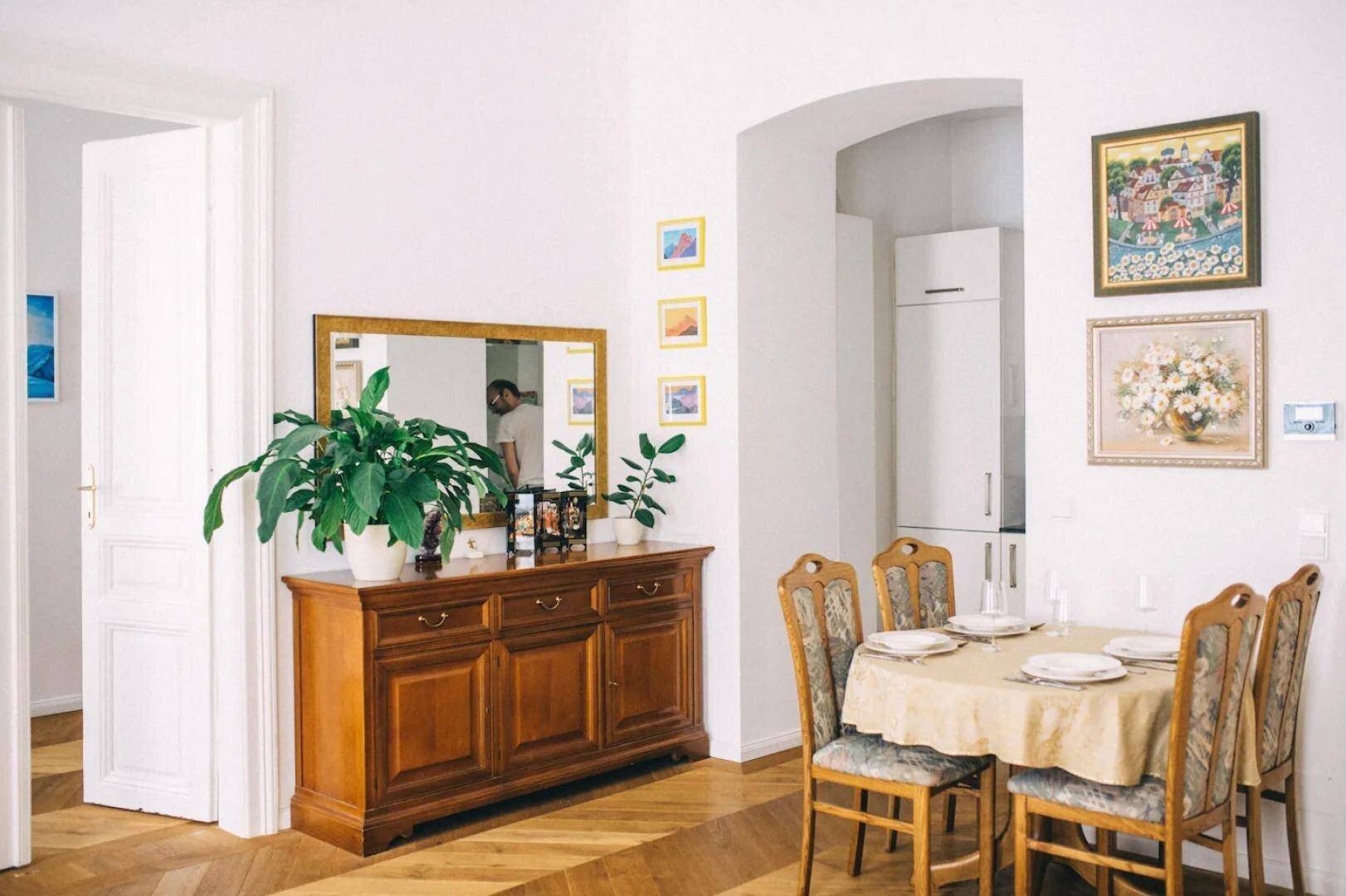 Essbereich mit klassischem Holzsideboard, Spiegel und Fischgrätparkettboden.