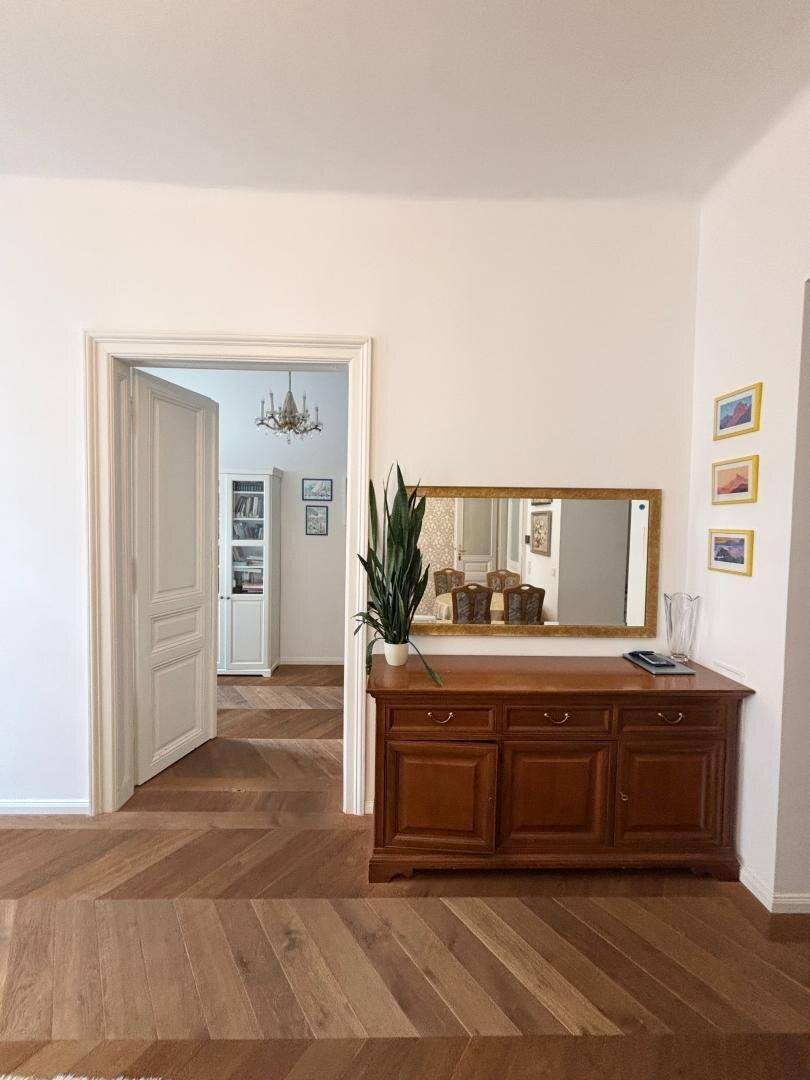 Übergangsbereich mit Holzkommode, Spiegel und Blick in angrenzende Räume.