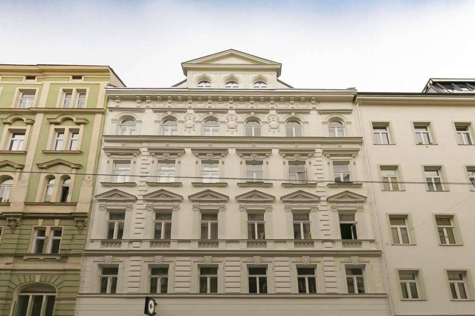 Historische Fassade eines Altbaus mit reich verzierten Details und vielen Fenstern.