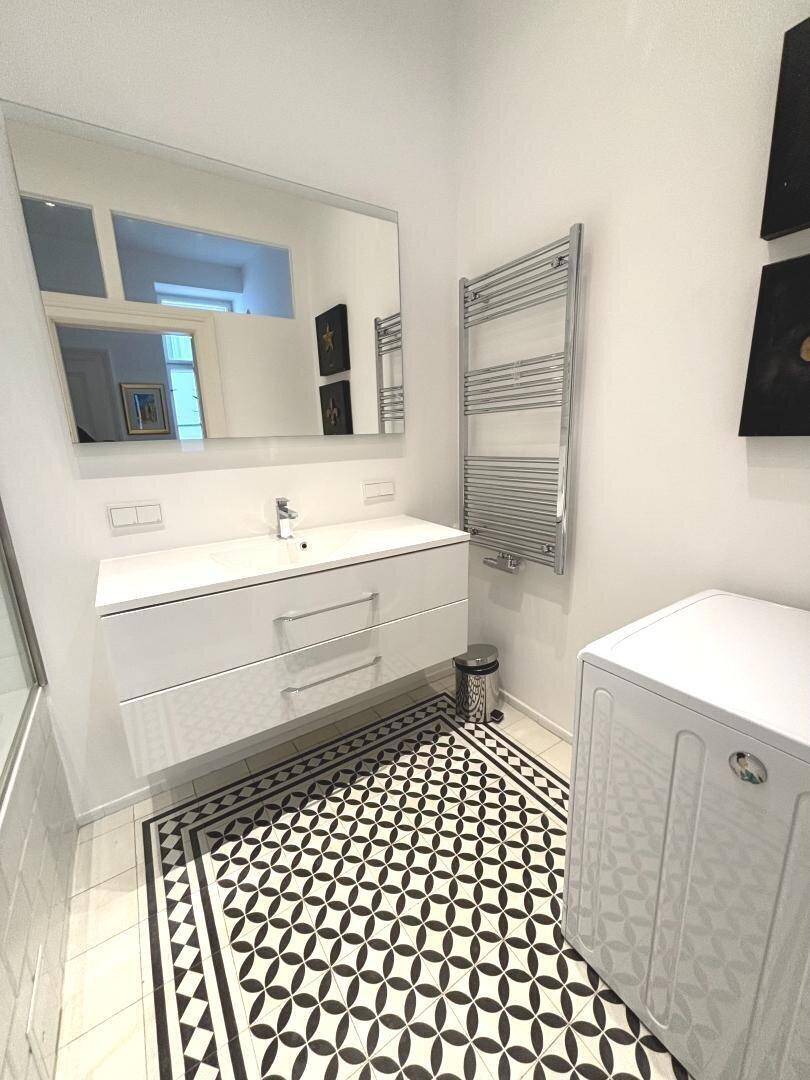 Modernes Badezimmer mit Waschbeckenunterschrank, großem Spiegel und Handtuchheizkörper.