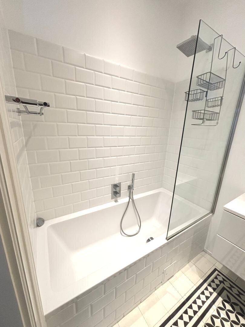 Modernes Badezimmer mit Badewanne, Regendusche und weißen Metrofliesen.