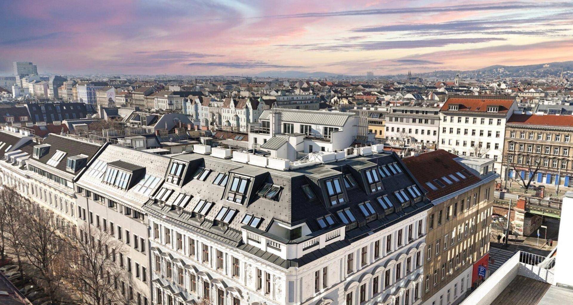 Panoramablick über die Stadt mit zahlreichen Gebäuden und Dachgeschosswohnungen bei Sonnenuntergang.