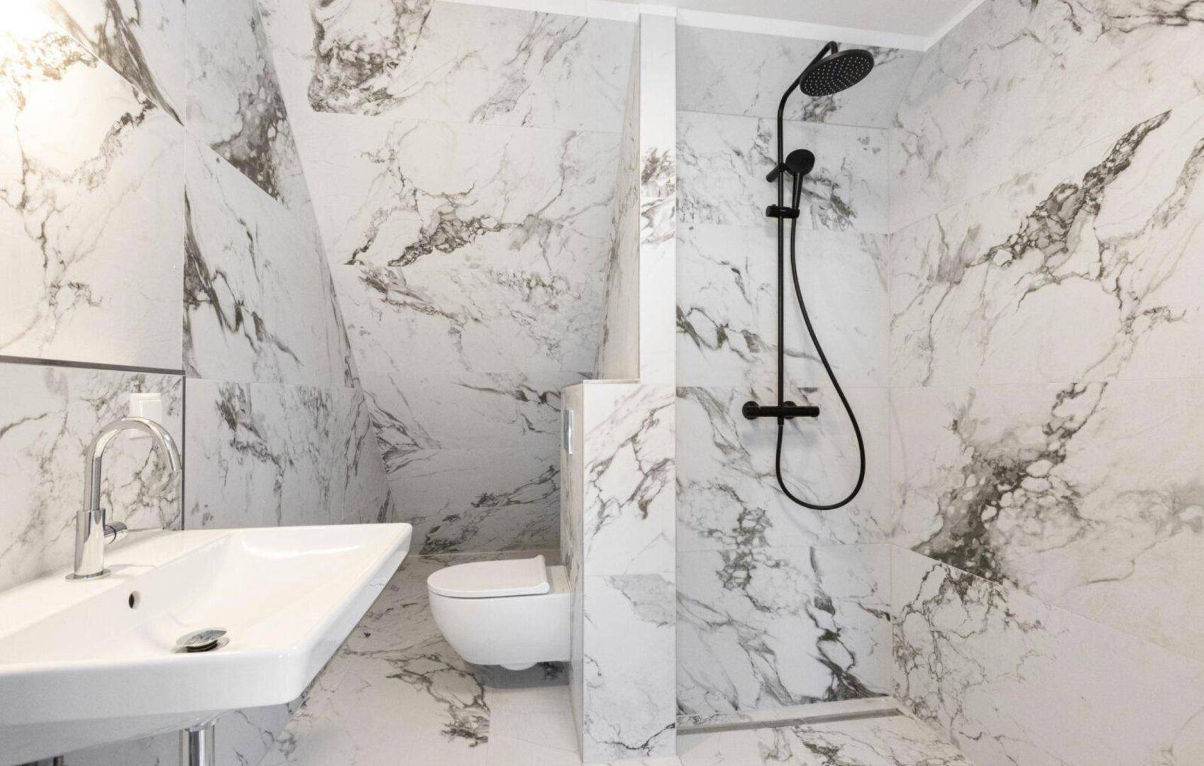 Elegantes Badezimmer mit Marmoroptik-Fliesen, wandhängendem WC und moderner Regendusche.