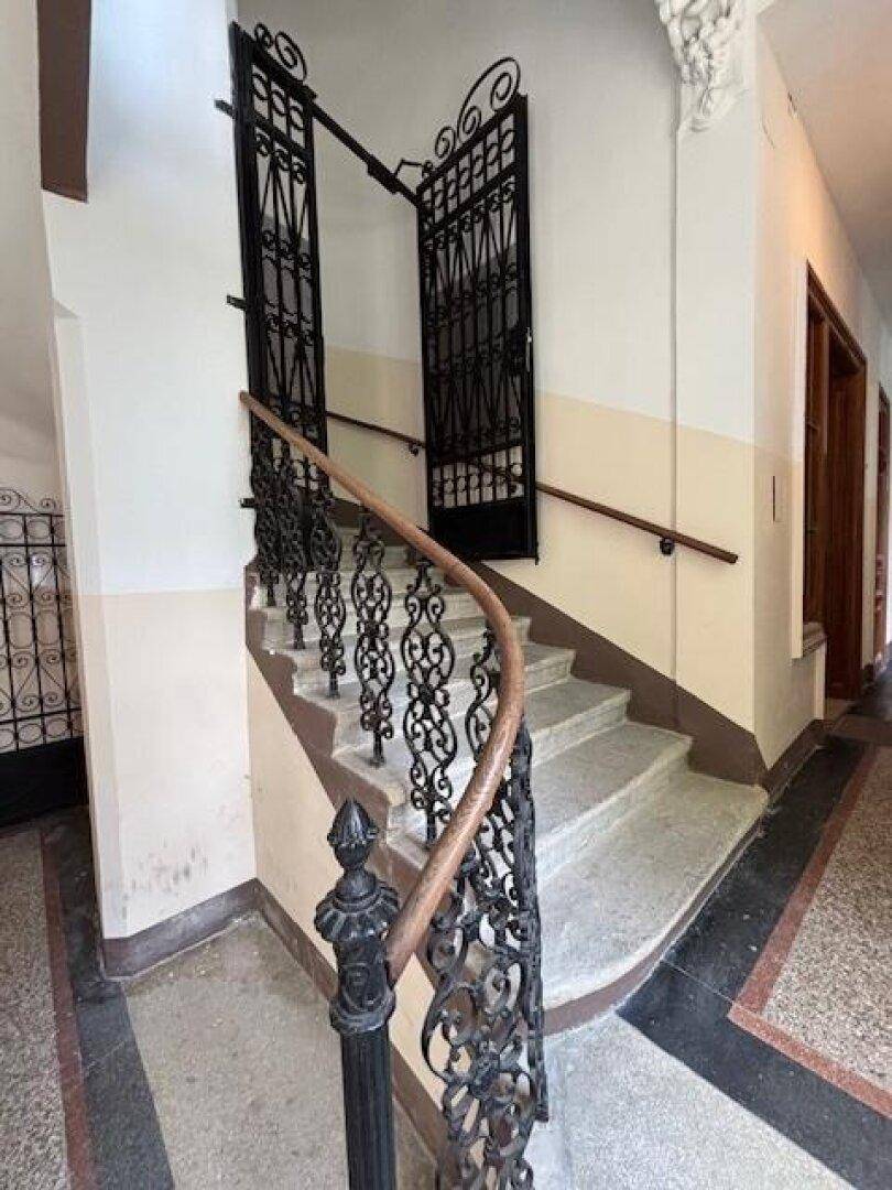 Historisches Treppenhaus mit schmiedeeisernem Geländer, Steinstufen und klassischem Charme.