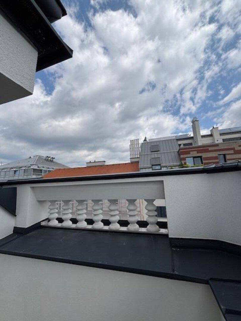 Dachterrasse mit Balustrade und weitem Blick über die Dächer der Stadt.