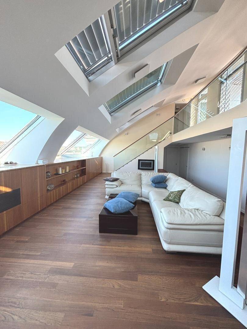 Heller Wohnbereich mit gemütlichem Sofa, Holzboden und integriertem Kamin unter den Dachschrägen.